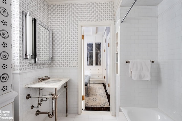 full bath featuring wallpapered walls, tile walls, wainscoting, tile patterned flooring, and a shower