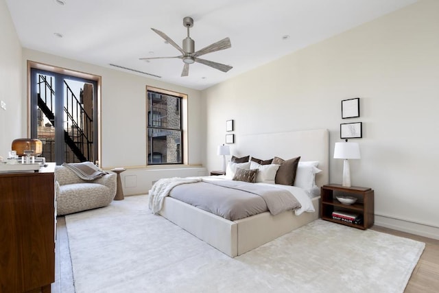 bedroom with ceiling fan, light wood-style flooring, and baseboards