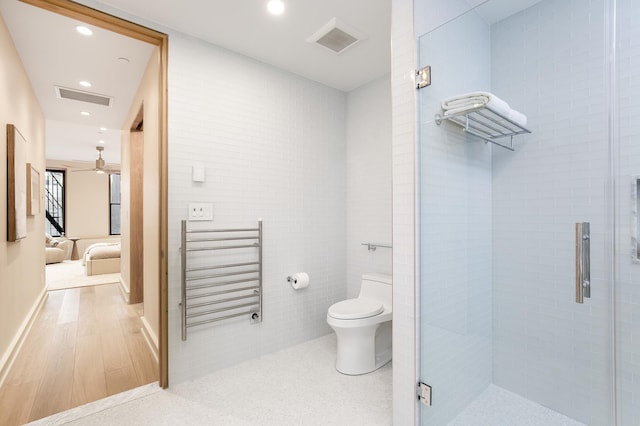 bathroom with tile walls, toilet, a shower stall, and radiator heating unit