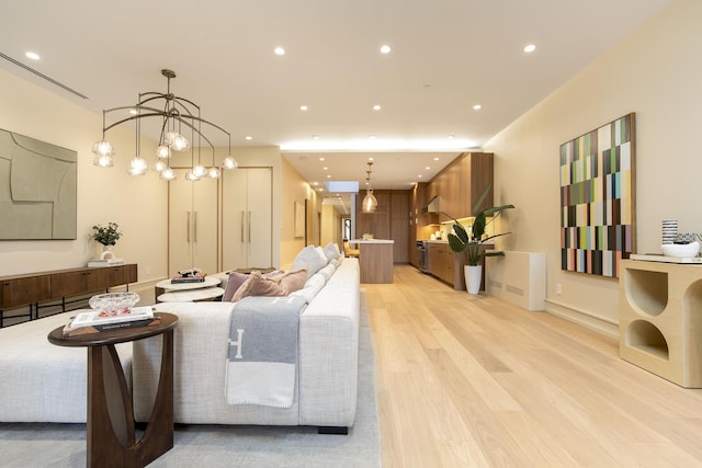 living area with light wood finished floors, a notable chandelier, and recessed lighting