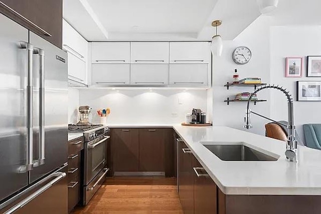 kitchen with light countertops, a sink, dark brown cabinets, modern cabinets, and high quality appliances