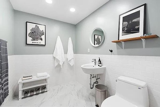 214 N 11th St Unit 1L, New York City, NY 11211 - bathroom featuring marble finish floors, toilet, tile walls, recessed lighting, and wainscoting