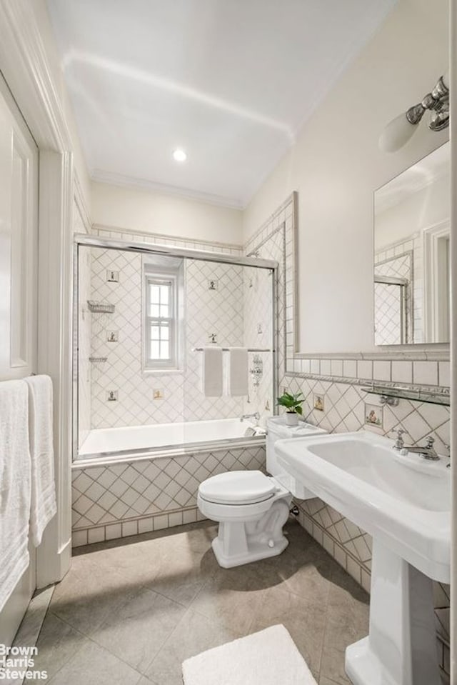 bathroom with tile walls, ornamental molding, toilet, and tiled shower / bath combo