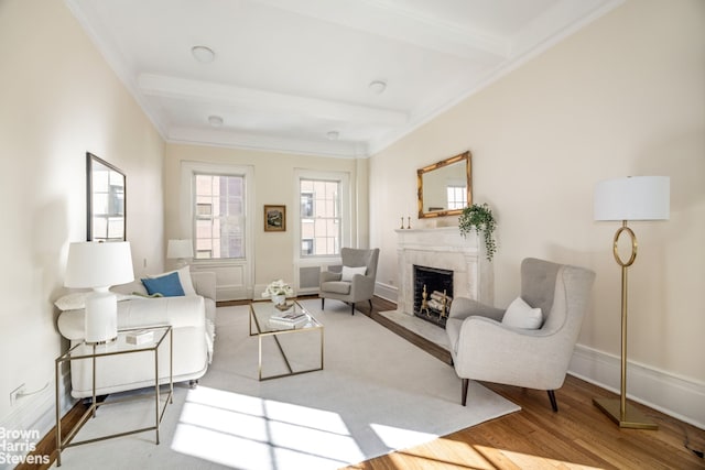 living room with beam ceiling, wood finished floors, crown molding, a premium fireplace, and baseboards