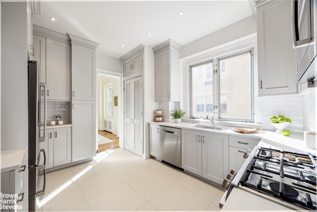 kitchen featuring backsplash, gray cabinetry, stainless steel appliances, and light countertops