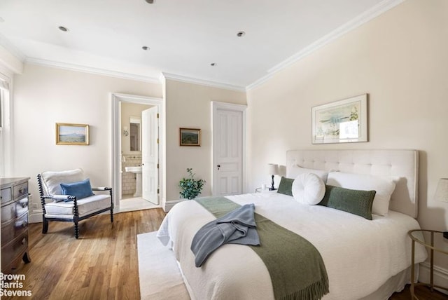 bedroom with connected bathroom, baseboards, wood finished floors, and ornamental molding