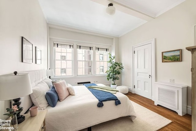 bedroom with ornamental molding and wood finished floors