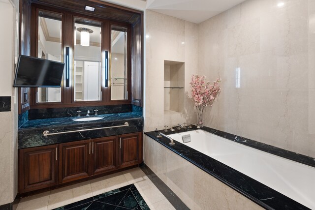 bathroom featuring tile patterned floors, vanity, tile walls, and tiled tub