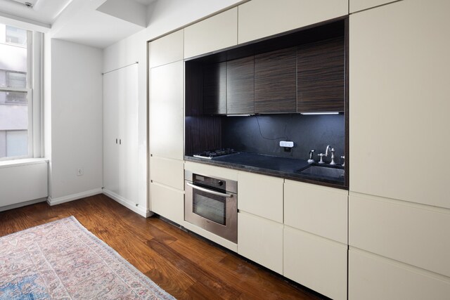 kitchen featuring dark hardwood / wood-style floors, white cabinetry, sink, oven, and gas cooktop