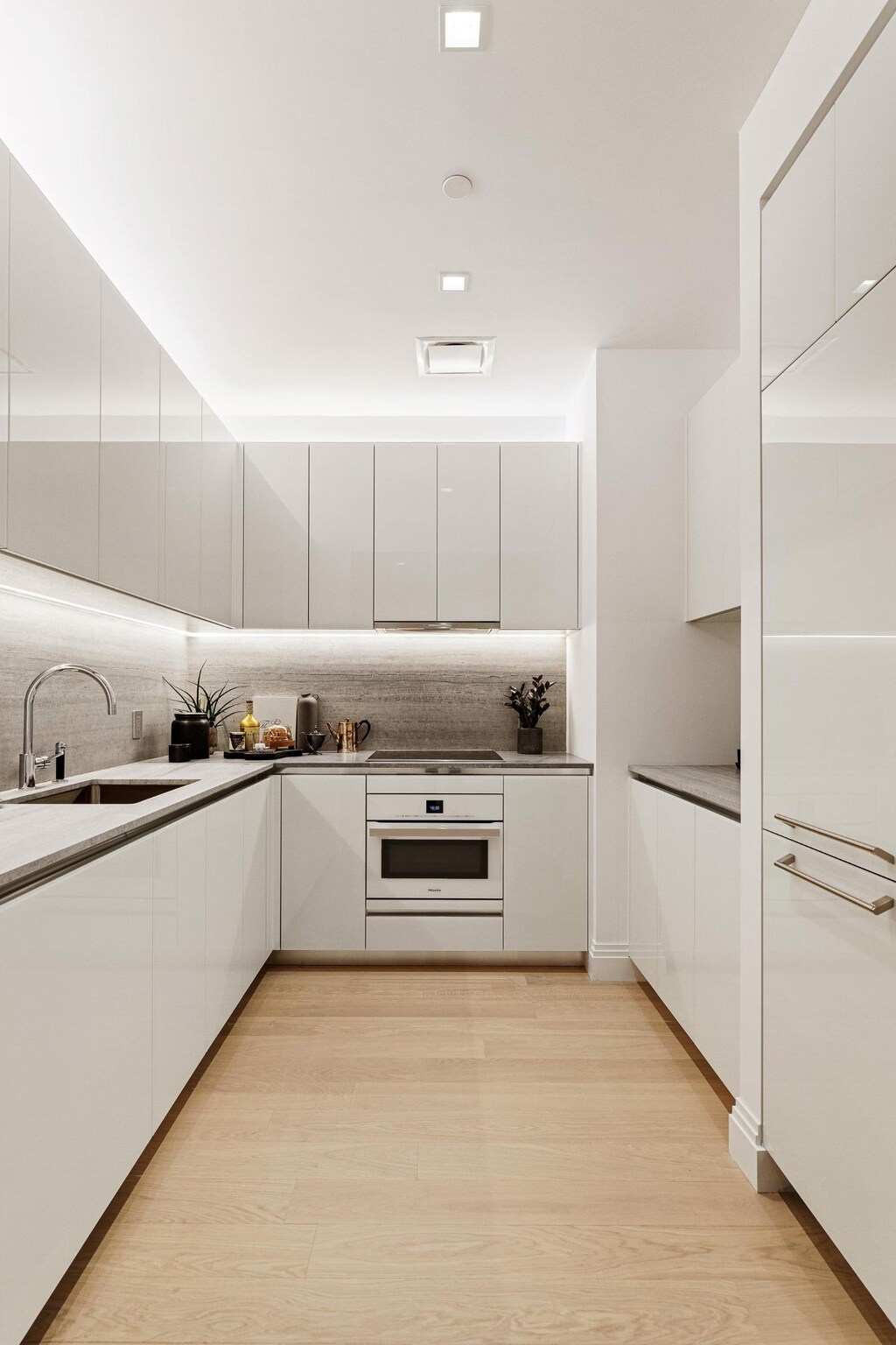 kitchen with sink, tasteful backsplash, light hardwood / wood-style floors, white oven, and white cabinets