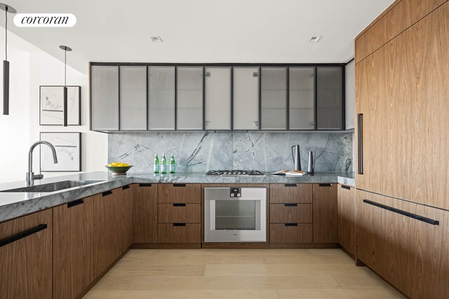 kitchen with dark stone counters, appliances with stainless steel finishes, decorative backsplash, and a sink