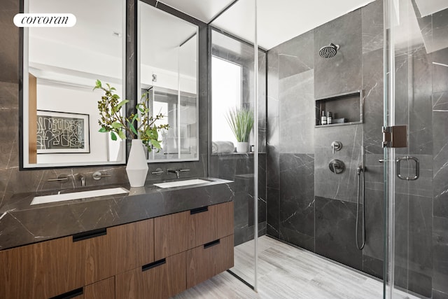 full bathroom with double vanity, a sink, and a shower stall