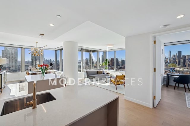 kitchen featuring sink, pendant lighting, a notable chandelier, and light hardwood / wood-style flooring