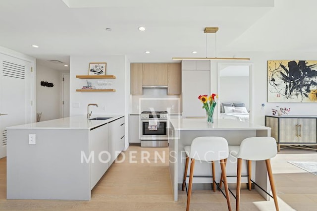 kitchen with a center island with sink, stainless steel range with gas cooktop, pendant lighting, and white cabinets