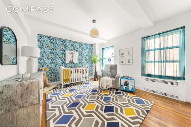 sitting room featuring radiator, hardwood / wood-style floors, and beamed ceiling