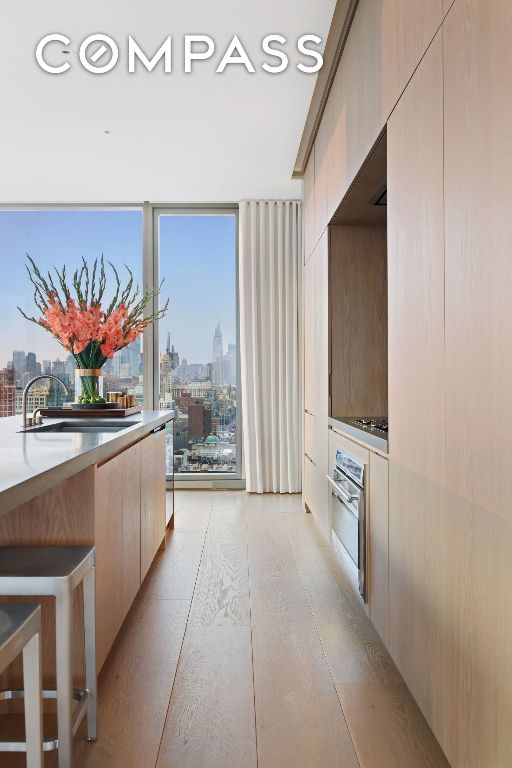 kitchen featuring a wall of windows, light countertops, a city view, stainless steel oven, and modern cabinets