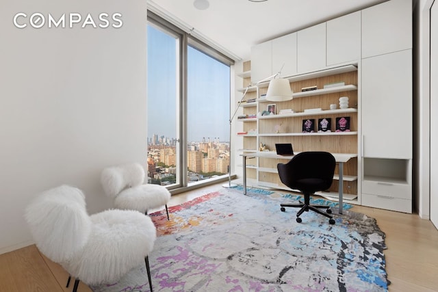 home office with expansive windows, a city view, and wood finished floors