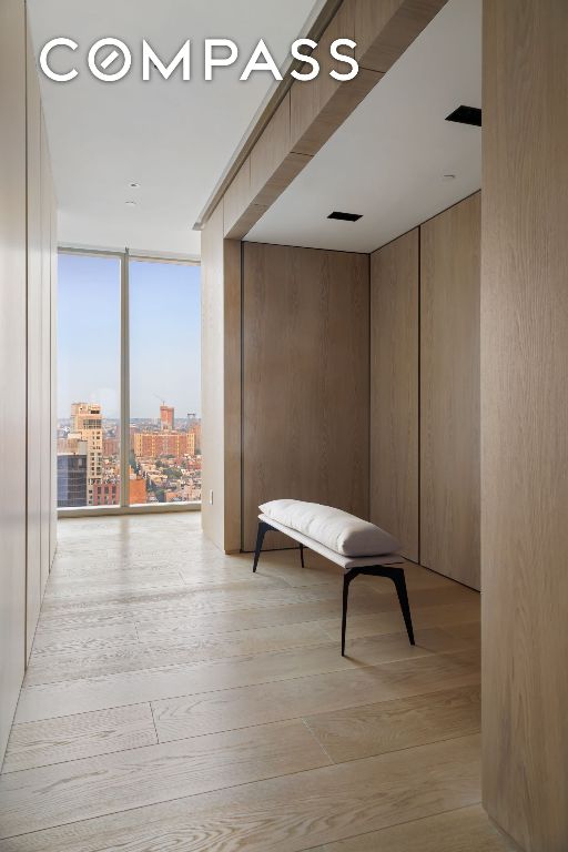 corridor featuring light wood finished floors, a city view, and a wall of windows