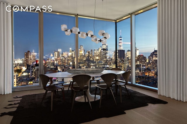 dining space featuring a view of city, a wall of windows, and wood finished floors