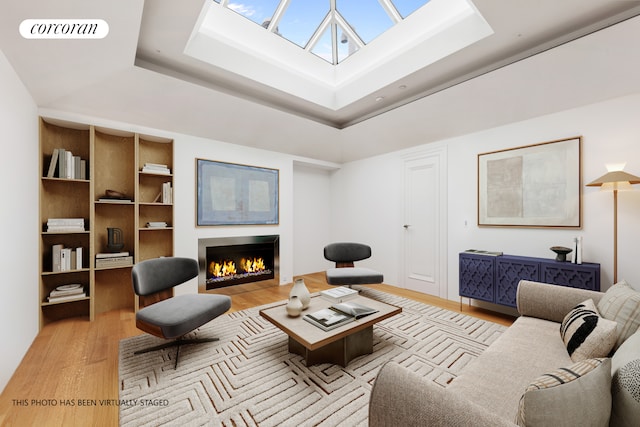 living area with a warm lit fireplace, light wood-style flooring, visible vents, and a skylight