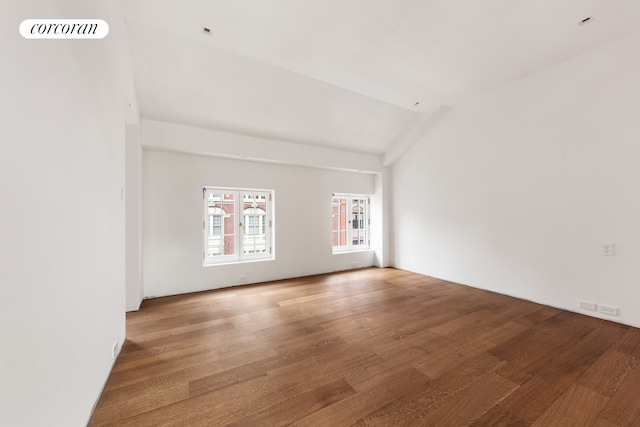 empty room featuring lofted ceiling, wood finished floors, and visible vents