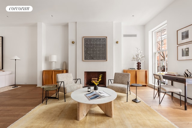 living area featuring a fireplace, wood finished floors, and visible vents