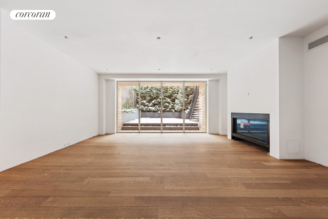unfurnished living room with a fireplace, wood finished floors, and visible vents