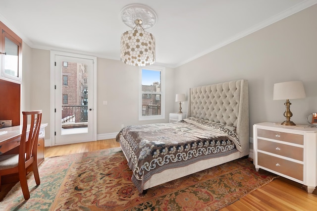 bedroom featuring baseboards, ornamental molding, wood finished floors, and access to exterior