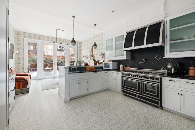 kitchen featuring a peninsula, dark countertops, white microwave, wallpapered walls, and double oven range