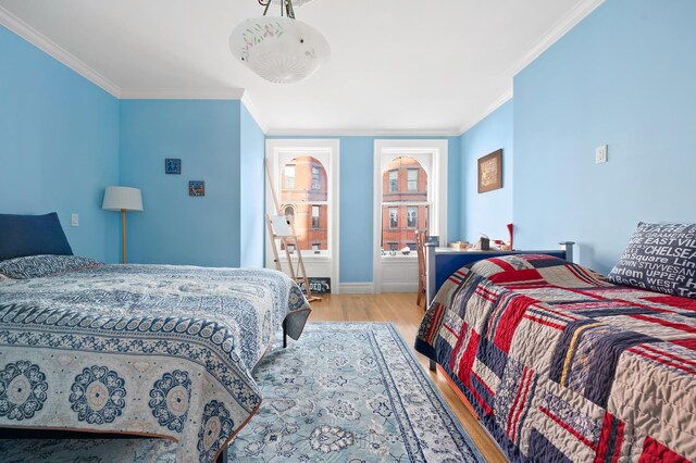 bedroom with baseboards, ornamental molding, and wood finished floors