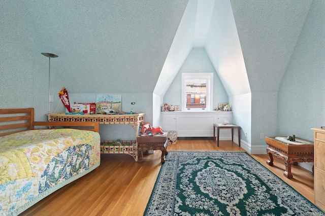 bedroom with lofted ceiling, a textured ceiling, and wood finished floors