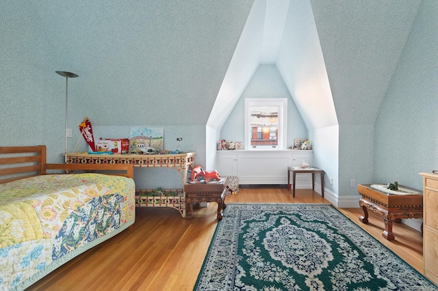 bedroom with lofted ceiling and wood finished floors