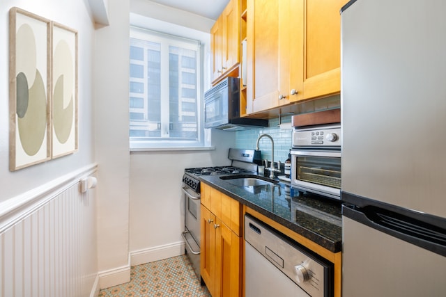 kitchen featuring appliances with stainless steel finishes, sink, dark stone countertops, and backsplash