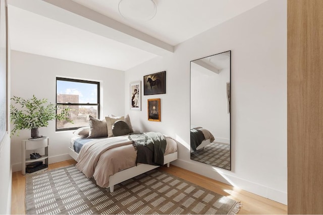 bedroom with wood-type flooring and beam ceiling