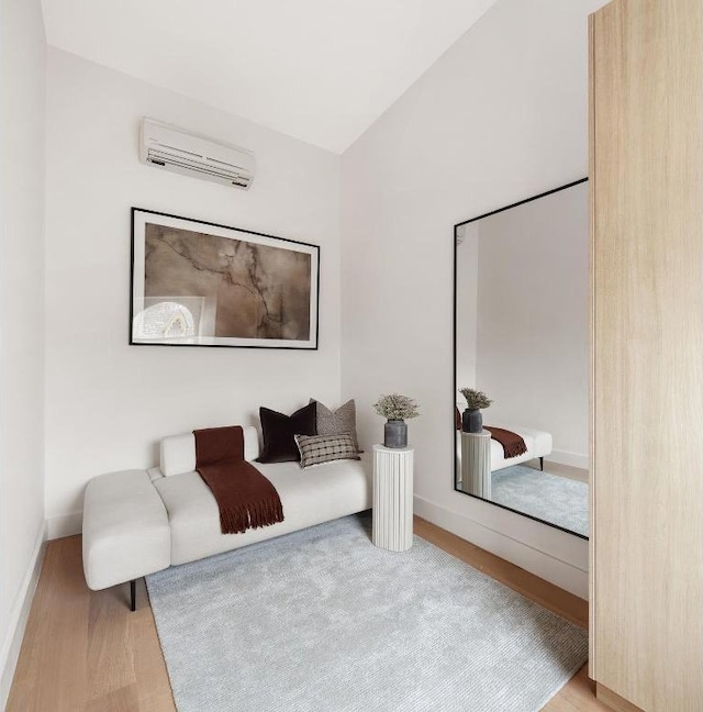 sitting room featuring lofted ceiling, a wall mounted air conditioner, and light hardwood / wood-style floors