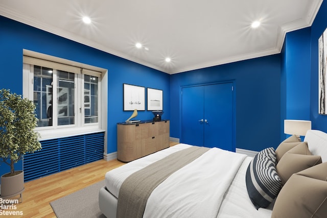 bedroom featuring wood-type flooring, ornamental molding, and a closet