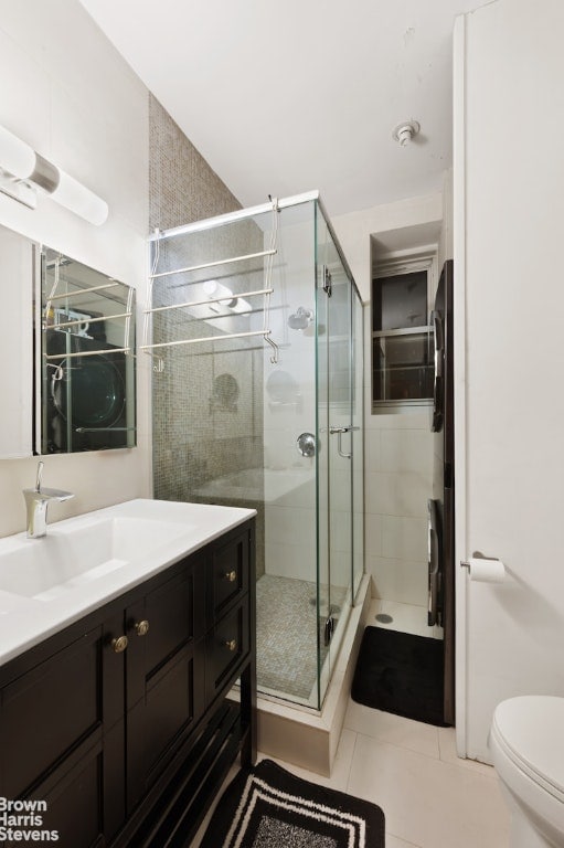 bathroom featuring vanity, tile patterned flooring, a shower with door, and toilet