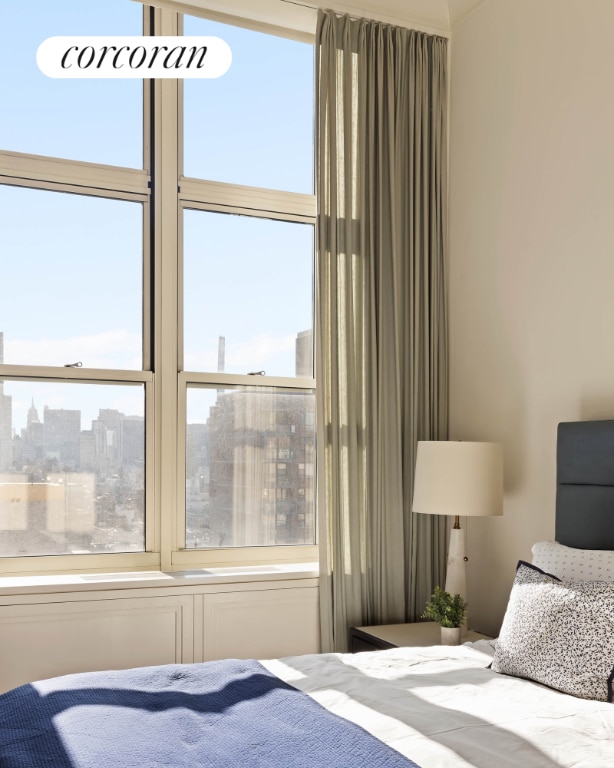 bedroom with a view of city and multiple windows