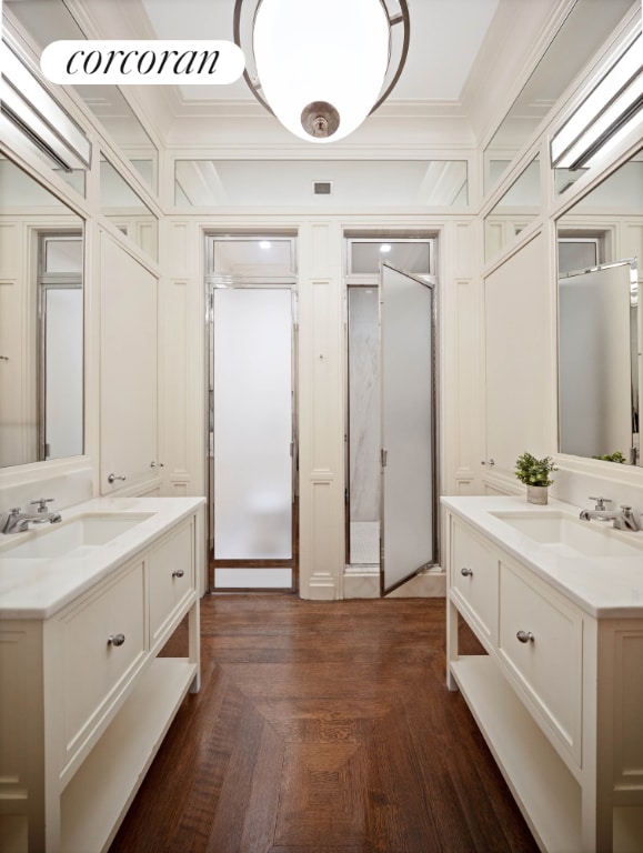 bathroom featuring a shower stall, ornamental molding, two vanities, and a sink