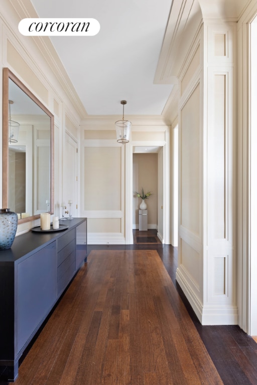 corridor with crown molding, dark wood finished floors, visible vents, and a decorative wall