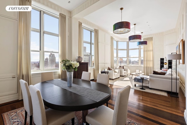 dining area with a city view, dark wood-style flooring, and a decorative wall