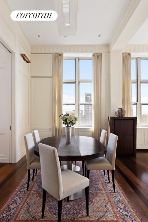 dining room featuring dark wood-type flooring, a decorative wall, and a wealth of natural light