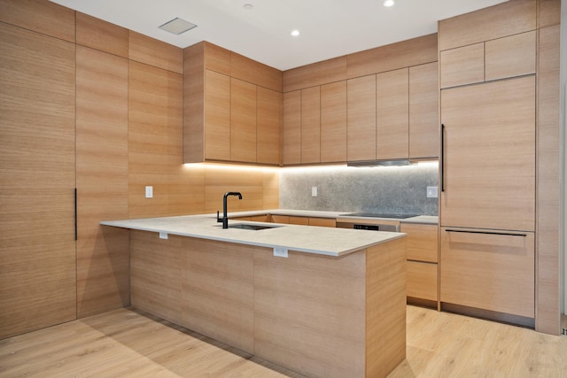 kitchen with light countertops, a sink, light wood-type flooring, a peninsula, and black electric cooktop