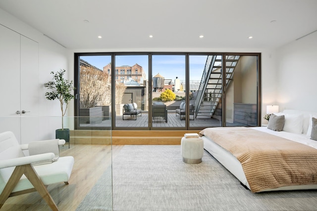 bedroom featuring access to exterior, expansive windows, recessed lighting, and wood finished floors