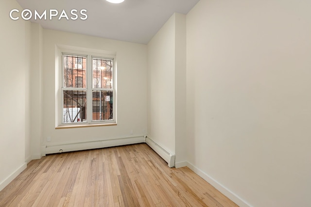 unfurnished room with light wood finished floors, a baseboard radiator, and baseboards