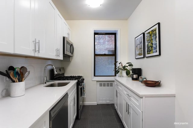 kitchen featuring radiator heating unit, white cabinetry, stainless steel appliances, and light countertops