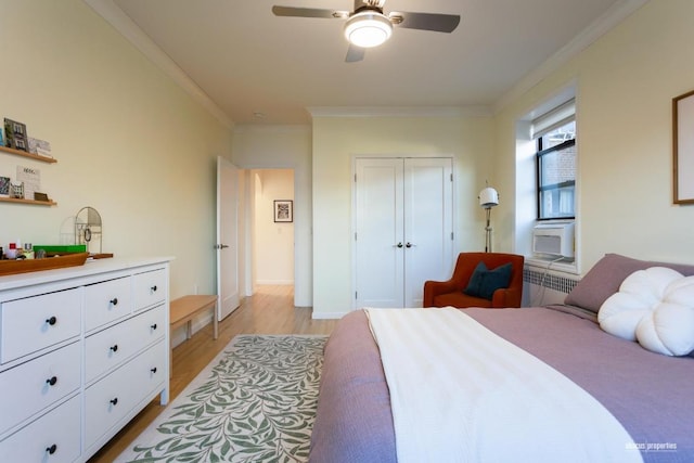 bedroom with light wood finished floors, a ceiling fan, radiator, crown molding, and a closet