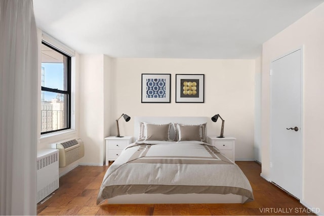 bedroom featuring hardwood / wood-style flooring, radiator heating unit, and a wall unit AC