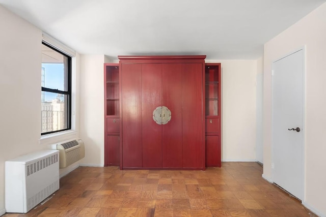 corridor featuring light parquet flooring, radiator heating unit, and a wall mounted AC