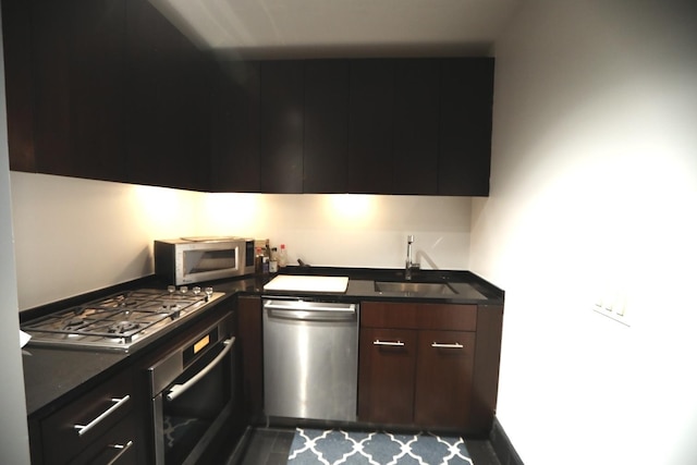 kitchen featuring dark countertops, appliances with stainless steel finishes, modern cabinets, and a sink